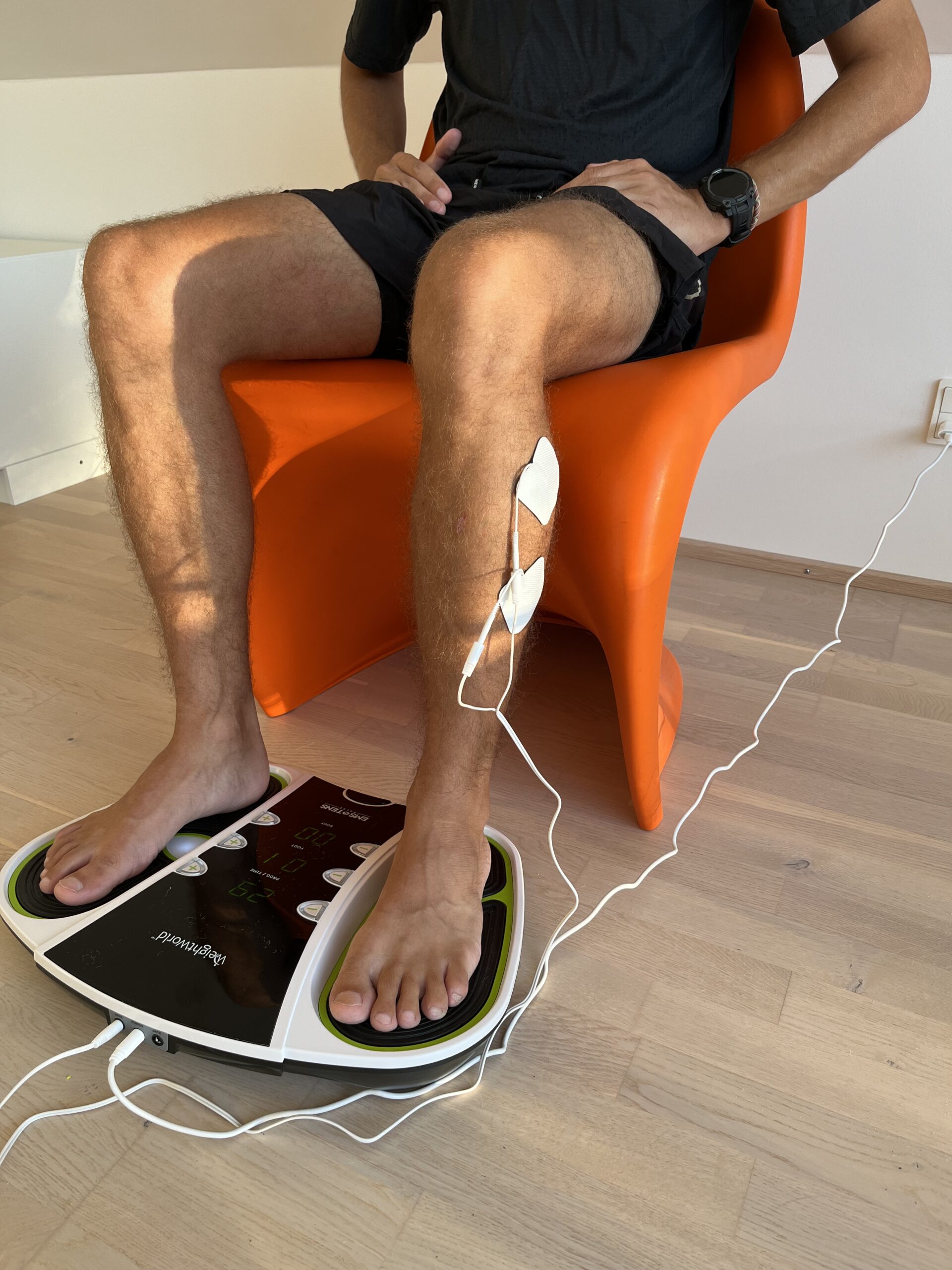 WeightWorld Cirkulationstræner - Person Sidder På En Stol Med Fødderne Placeret på Cirkulationstræneren